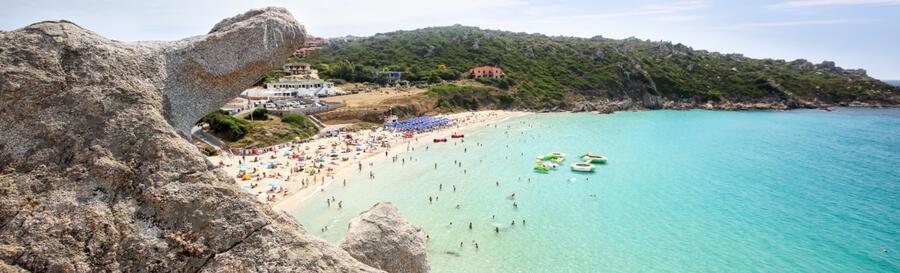 People relaxing on a wooden sun deck and gray sand at Spiaggia di Santa Teresa in central Salerno.