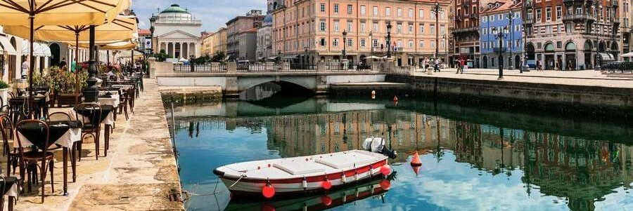 Canal and cafes near Trieste Port with outdoor seating and historic buildings