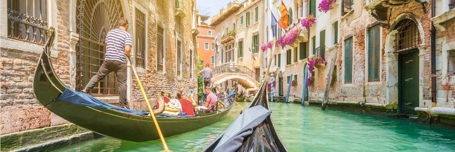 Gondola ride through a narrow canal in Venice with buildings and flowers