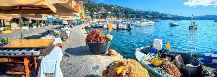 Villefranche-sur-Mer waterfront with colorful buildings, boats, and seaside restaurants along the harbor in the French Riviera