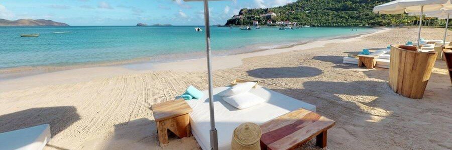 Beach loungers and umbrellas on the white sand at Nikki Beach St. Barts.