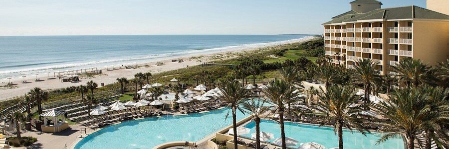 Aerial view of Omni Amelia Island Resort & Spa featuring beachfront pools, palm trees, and ocean views in Florida.