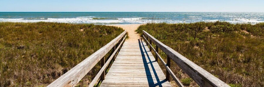 Wooden boardwalk leading through dunes to Ponte Vedra Beach and the Atlantic Ocean.