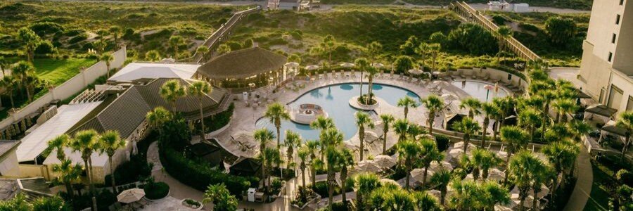 Aerial view of The Ritz-Carlton Amelia Island resort pool surrounded by palm trees and beachfront grounds in Florida.