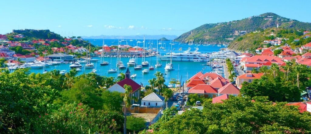 Sleek white luxury catamaran anchored in the crystal-clear turquoise waters of St Barts.