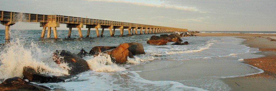 Waves crashing against rock jetties next to the long ocean fishing pier at Fort Clinch State Park in Fernandina Beach.