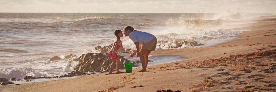 Family enjoying a sunny day along the sandy shoreline in Jensen Beach, Florida.