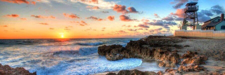 Sunrise over the rocky shoreline at Jensen Beach, Florida with waves crashing along the Atlantic coast.