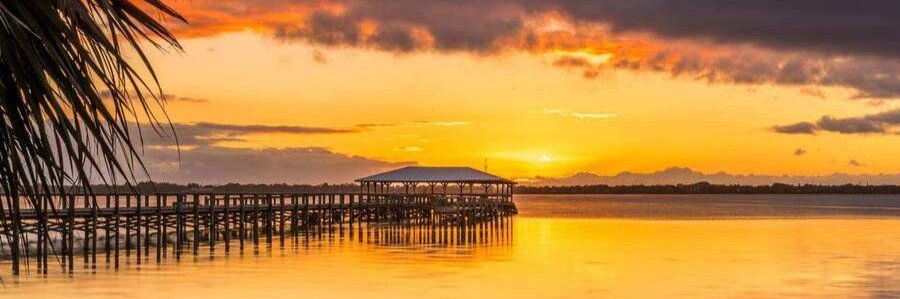 Sunset over the Indian River Lagoon with a long wooden pier in Melbourne, Florida.