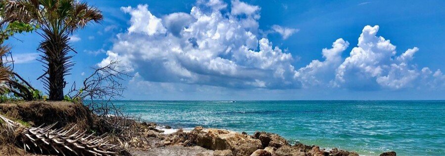 Rocky shoreline and turquoise Atlantic Ocean near Port Salerno, Florida beneath dramatic coastal clouds.