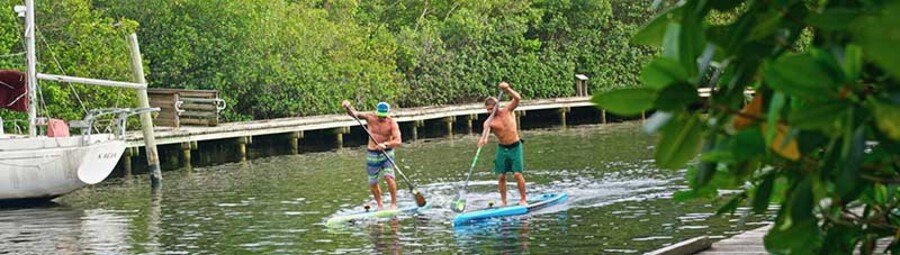 Visitors paddleboarding through calm waterways in Port Salerno near Hobe Sound, Florida.