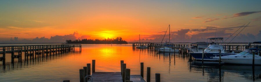 Sunset Along the Sebastian Riverfront | Beach Travel Destinations Boats and wooden docks along the Sebastian riverfront during a vivid orange sunset