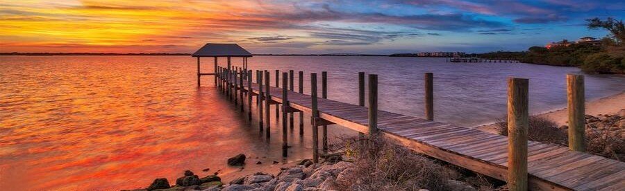 Colorful sunset over a wooden fishing pier along the Stuart waterfront in Florida.