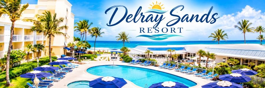 Oceanfront resort with a curved turquoise swimming pool, navy blue umbrellas, tropical palm trees, and a beautiful sandy beach.