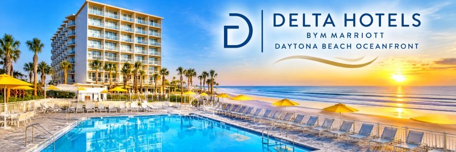 Delta Hotels by Marriott | Daytona Beach Oceanfront Oceanfront hotel with a sparkling swimming pool, yellow umbrellas, palm trees, and Atlantic Ocean views.