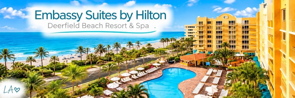 Embassy Suites by Hilton resort overlooking a turquoise swimming pool, palm-lined beachfront, and blue Atlantic Ocean in Deerfield Beach.