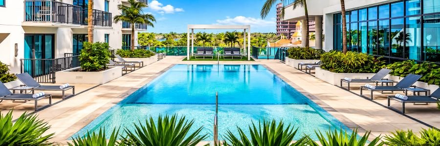Hotel AKA West Palm with a modern swimming pool, lounge chairs, palm trees, and tropical landscaping in West Palm Beach.