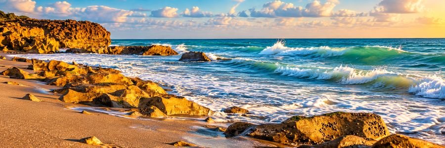 Rocky Jupiter Florida beach with Atlantic waves, turquoise water, and golden sunlight along the shoreline.