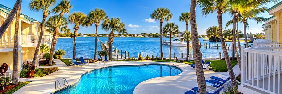 Jupiter Waterfront Inn with a tropical swimming pool, palm trees, waterfront docks, and boats in Jupiter Florida.