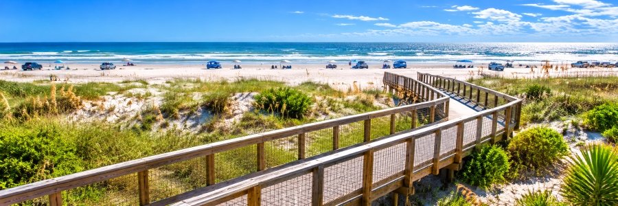 Ponce Inlet | Best Area Beaches Ponce Inlet area beach with a wooden boardwalk winding through sandy dunes toward the Atlantic Ocean.