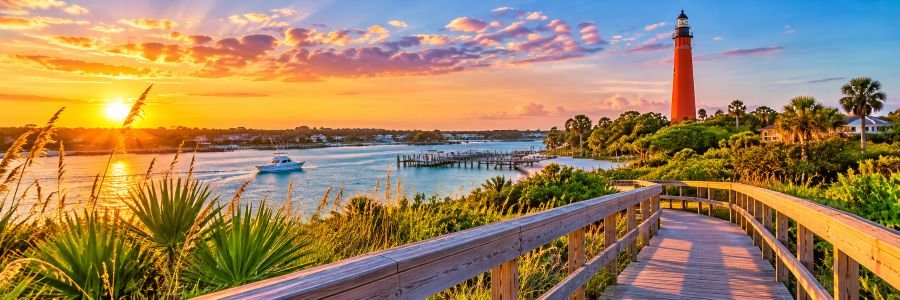 Ponce Inlet | Lighthouse & Coastal Beauty Ponce Inlet lighthouse overlooking a scenic coastal waterway, wooden boardwalk, and golden sunset.