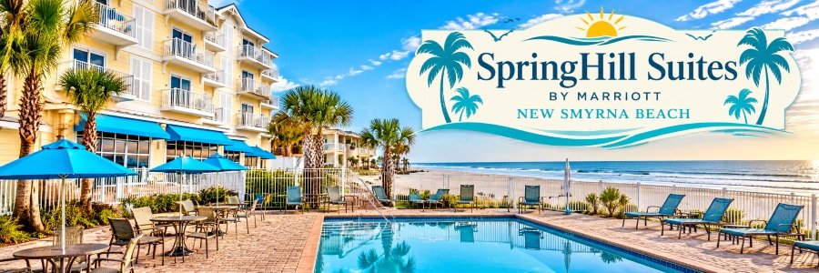 SpringHill Suites by Marriott | New Smyrna Beach Oceanfront hotel with a sparkling swimming pool, blue umbrellas, palm trees, and lounge chairs overlooking the Atlantic Ocean near Edgewater Florida.
