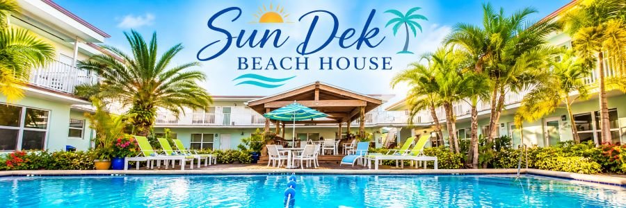 Sparkling turquoise swimming pool surrounded by tropical palm trees, colorful lounge chairs, and pastel-colored boutique hotel buildings.