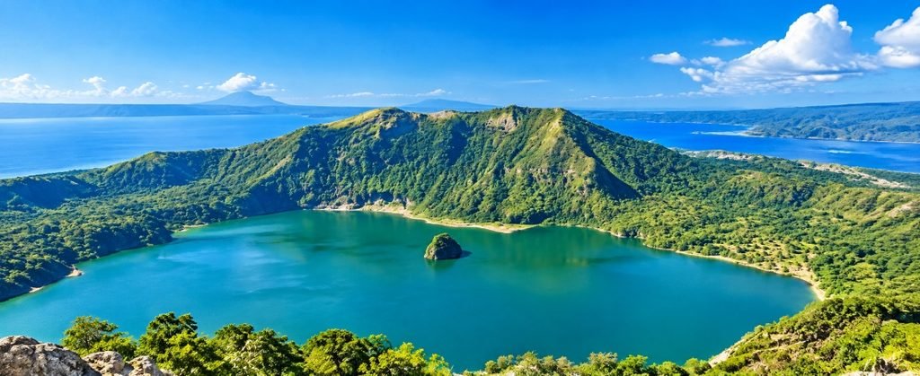 Taal Volcano Batangas | Spectacular Crater Lake Views Panoramic view of Taal Volcano in Batangas with a turquoise crater lake, lush green volcanic slopes, and blue skies.
