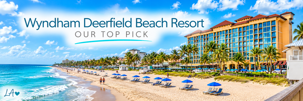 Wyndham Deerfield Beach Resort overlooking turquoise Atlantic waters, a sandy shoreline, blue beach umbrellas, and palm-lined oceanfront grounds.