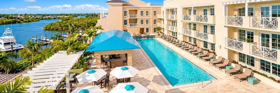 Wyndham Grand Jupiter at Harbourside Place with a turquoise swimming pool, tropical palms, marina, and waterfront views.